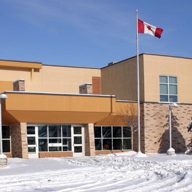 School building with Canadian flag in front on a snowy day