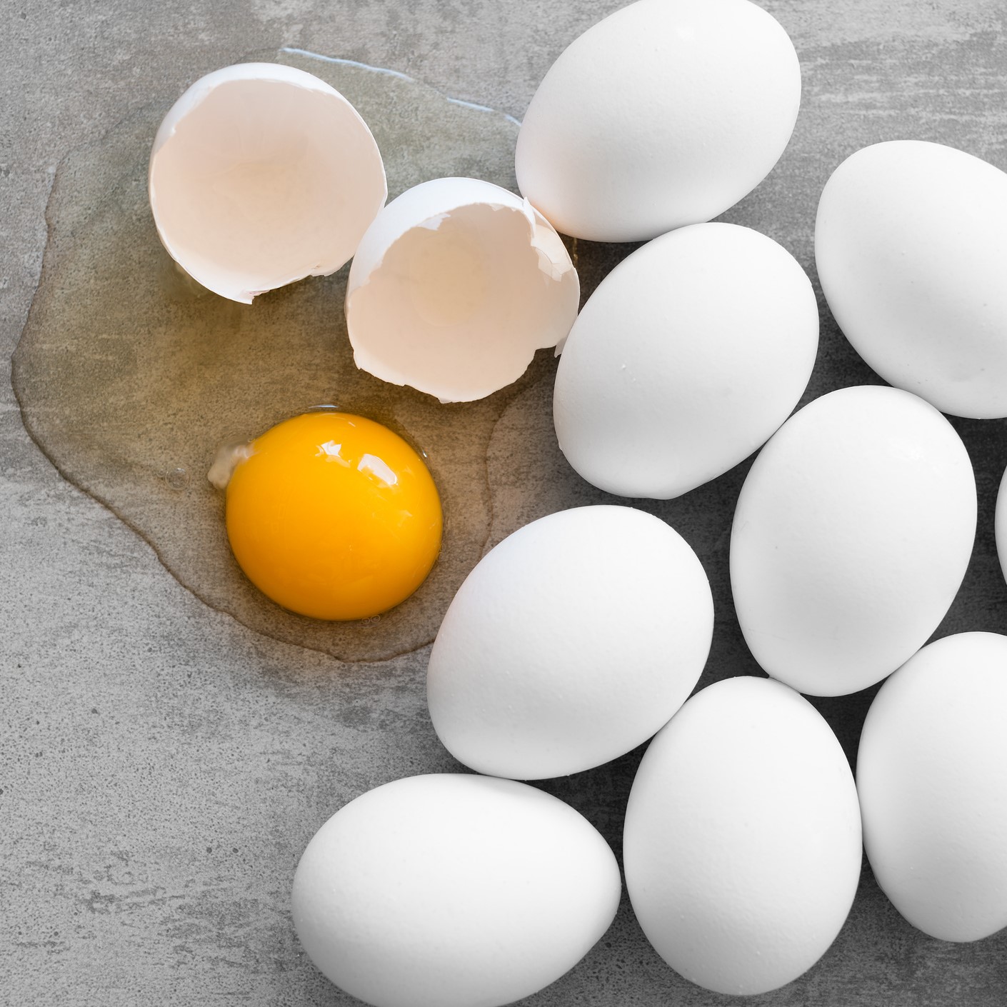 White eggs, one broken egg showing yolk